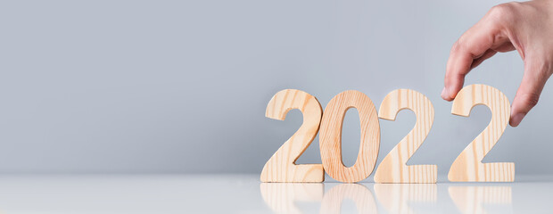 Close up hand pick happy new year 2022 down on white table and grey background.holiday celebration