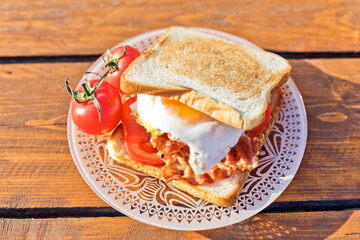 Breakfast in nature. Fried sandwich with egg, bacon, tomatoes 