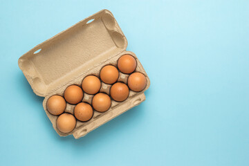 A cardboard box with ten eggs on a blue background.