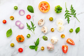 The ingredients for homemade pizza set up on white marble background.