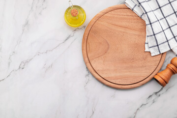 Empty wooden pizza platter with napkin  set up on marble stone kitchen table. Pizza board and tablecloth on white marble background.