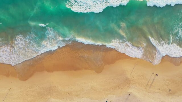 aerial top view The emerald green waves burst into white bubbles as they hit the beach..4K Videos for beautiful nature and unusual travel idea..beach sea sand and moving waves background....