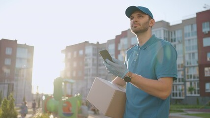 Male courier man is looking for mobile phone to deliver address of food from a shop. Delivery guy navigates in phone in city, searching for shop delivery addresses. Fast delivery