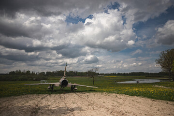 old vintage reactive airplane, plane in the field with dandelions, cloudy dramatic sky in the middle of early may day	