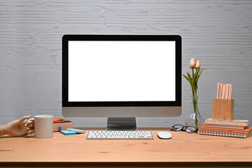 Fototapeta premium Mock up computer with stationery and coffee cup on wooden desk with brick wall.