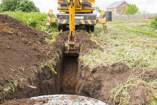 An excavator digs a trench for laying a water pipe