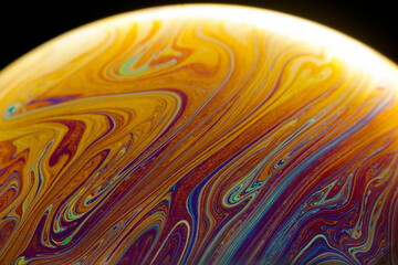 Abstract of a soap bubble. A mix of earth tones colors with black background.