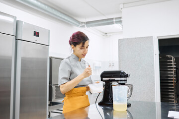 A bright girl cooks sweet dishes at a small production facility