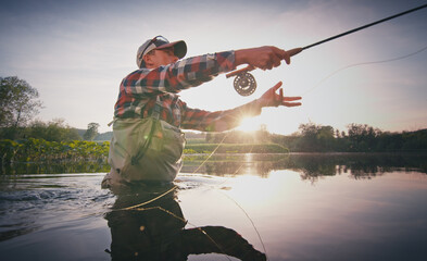 Fly fisherman stands in the water and casts the fly with fishing rod using Roll Cast with lot of splashes - 440367914