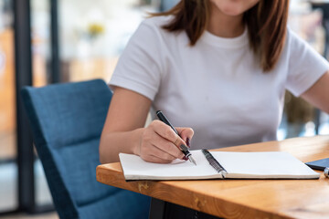 Close-up of a woman hand taking notes on paper with a pen sitting a chair in  office.