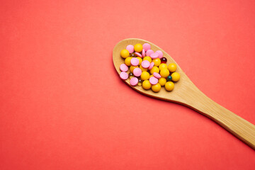 pills in a spoon on a red background top view antibiotics medicine