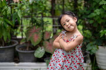 Girl with happy face expression standing arms crossed at garden.