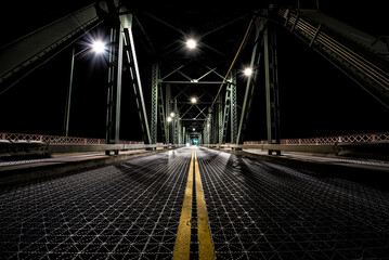 Night time photo from the center of the Hawthorne Bridge in Portland, Oregon. A straight, empty...
