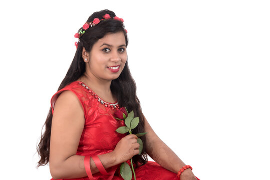 Beautiful young girl or woman holding and posing with red rose flower on white background