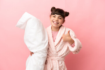 Little caucasian girl isolated on pink background in pajamas and with thumbs up because something good has happened