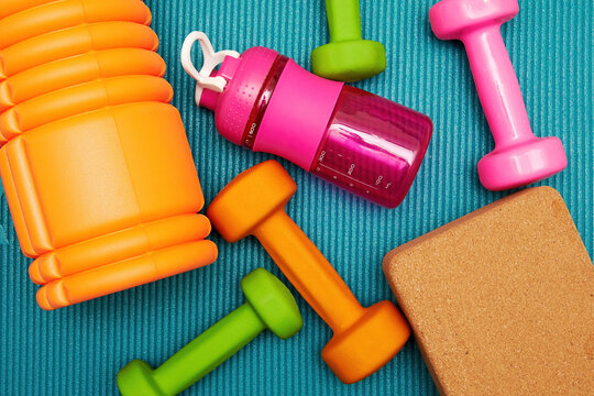 Scattered fitness objects, dumbbells, bricks and bottle on the mat in the gym. Bodycare and exercising backgrounds and symbols