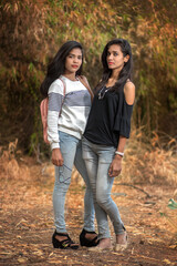 Fototapeta premium Two young girl friends standing together and having fun in outdoors. Looking at camera.