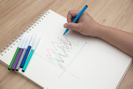 Photo of student hand using felt tip pen to draw chart on the notebook for homework