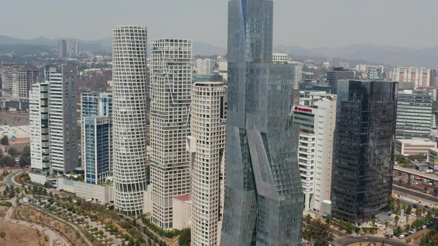 Aerial drone view of Torre Paradox and surrounding group of modern tall buildings. Camera panning and tilting down. Mexico city, Mexico.