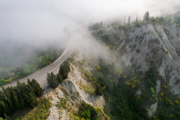 Karst landscape in Tuscany near Chiusure photographed with a drone. Fields, valley of Toscana, Siena region in Italy with little road and morning fog, mist. Small village of Chiusure.