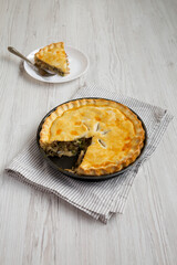 Homemade Chicken Pot Pie on a white plate on a white wooden background, side view.