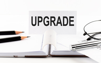 Text UPGRADE on paper card,pen, pencils, glasses,financial documentation on table - business concept