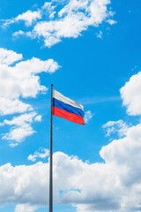 Russian flag: white, blue, red against the sky with clouds