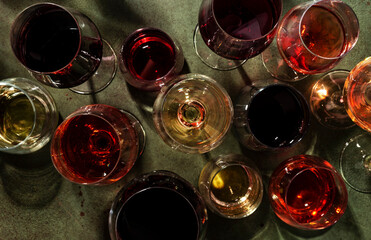 Red, rose and white wine in glasses on rusty green background, top view. Wine bar, shop, winery,...