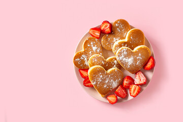 Heart pancakes with strawberry on pink plate