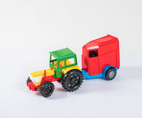 Plastic toy multicolored cars isolated on white background. Tractor with a van for transporting horses.