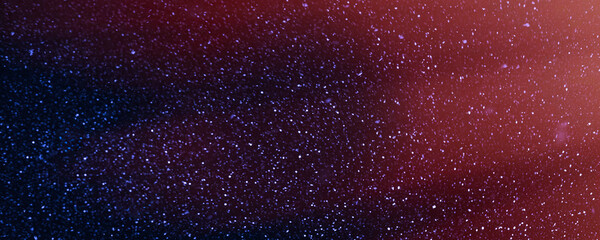 Night sky with falling snowflakes and red reflections, blurred winter background