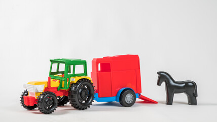 Plastic toy multicolored cars isolated on white background. Tractor with a van for transporting horses.