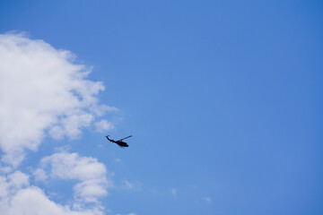 青空に爆音を轟かせながら飛ぶヘリコプター