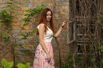 Young woman in pink dress near vintage brick wall