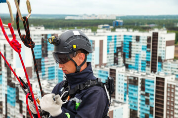 Industrial mountaineering worker in uniform on residential facade building