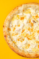 Pizza with cheese and pineapple on a yellow background.