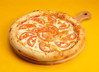 Pizza with cheese and tomato slices on a yellow background.