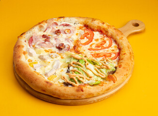 Assorted pizza. Tomatoes, sausage, chicken, pineapple, salad. On a yellow background.