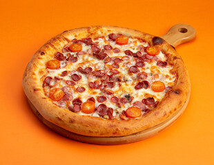 Pizza with sausages and tomatoes. On a yellow background.