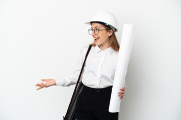 Young architect woman with helmet and holding blueprints isolated on white background with surprise expression while looking side