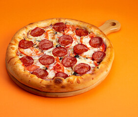 Pizza with pepperoni and tomato. On a yellow background.