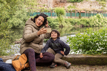 Fototapeta na wymiar mother and her daughter taking a selfie sitting next to a river