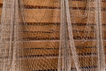 Wooden walls of the house covered with the fishing net, old and grange style. Abstract decoration.