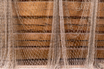 Wooden walls of the house covered with the fishing net, old and grange style. Abstract decoration.