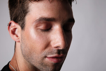 Close-up portrait of real man face looking at camera on grey background.