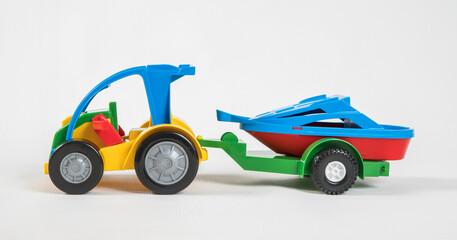 Plastic toy multicolored cars isolated on white background. A car with a motor boat on a trailer.