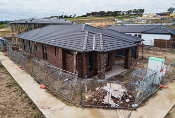 An aerial view of a house being built, with the roof on and most of the brickwork complete the...