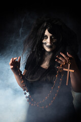 Bride cadaver with black veil holding a large rosary black background, Low Key portrait, selective focus.