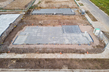 An aerial view of a freshly laid concrete house slab in a new development stage in the suburbs of Melbourne Australia, surrounding land is clear and construction is ready to begin on the frame stage.