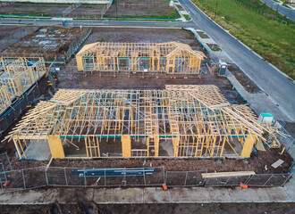 An aerial view of three houses on a corner during the frame stage of construction, almost like a...